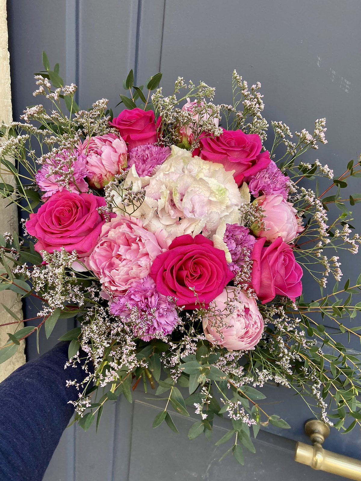 Bouquet rond de roses roses et fuchsia, tenu à bout de bras