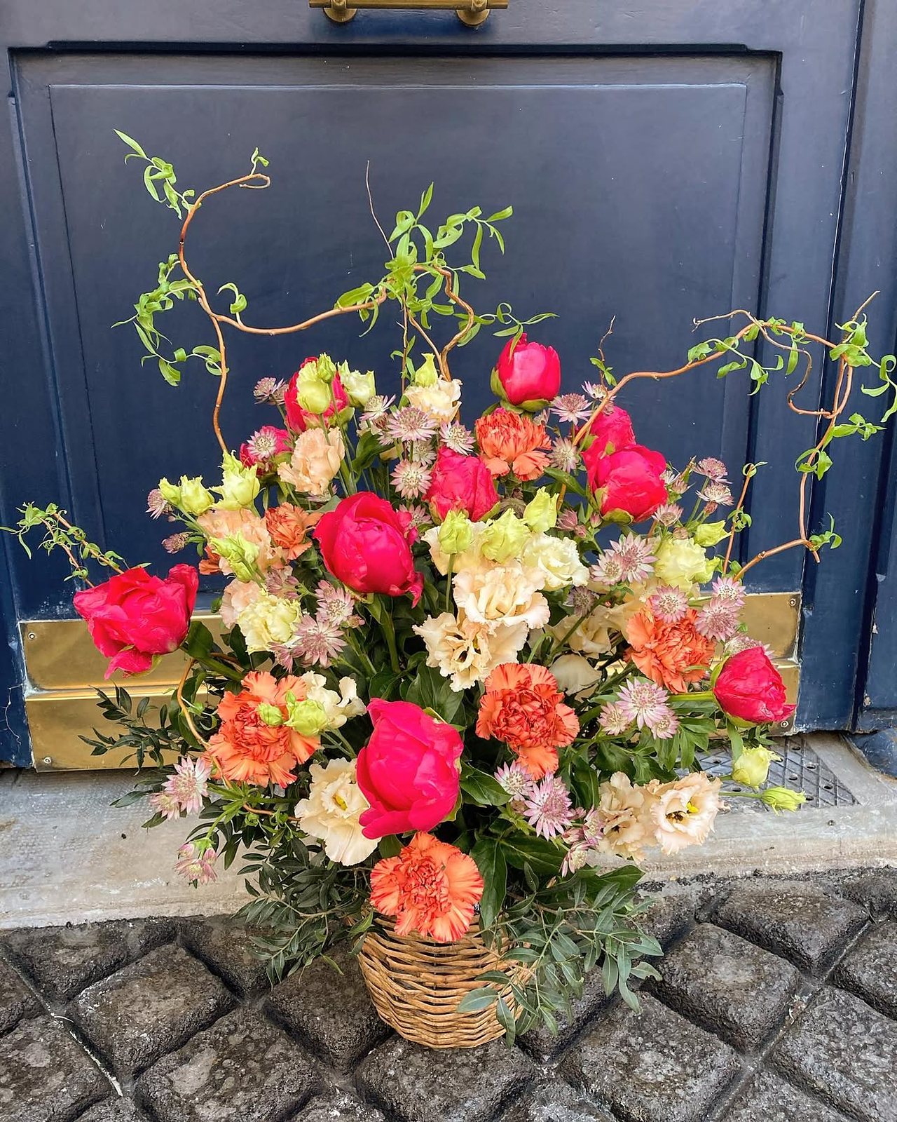 Composition rouge et corail dans un panier, devant une porte bleue