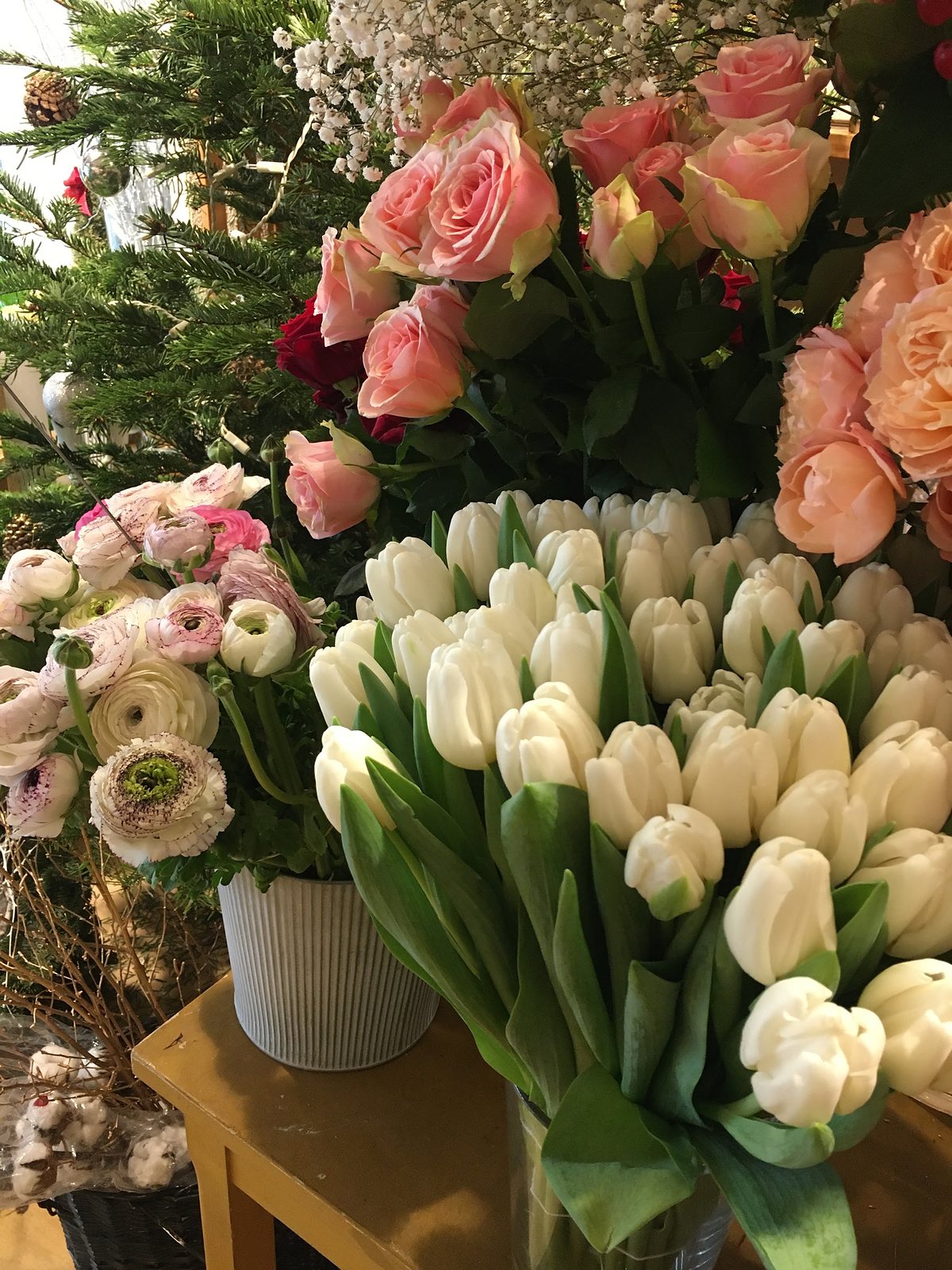 Roses pêche et tulipes blanches devant la vitrine